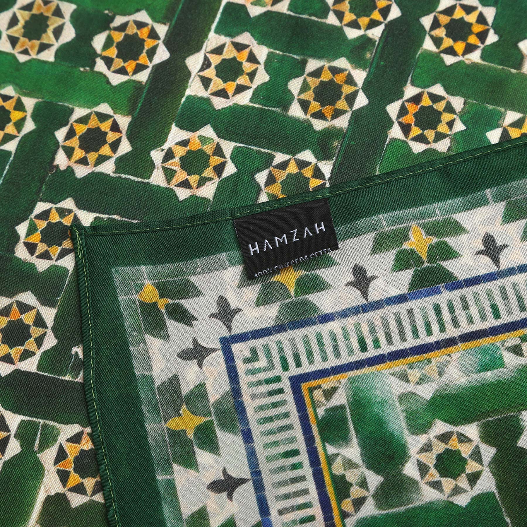 The Green Square Scarf Silk features yellow and white geometric star and tile designs inspired by Alhambra Palace Islamic art, with a black HAMZAH label on the hem and an intricate decorative border along the edge.