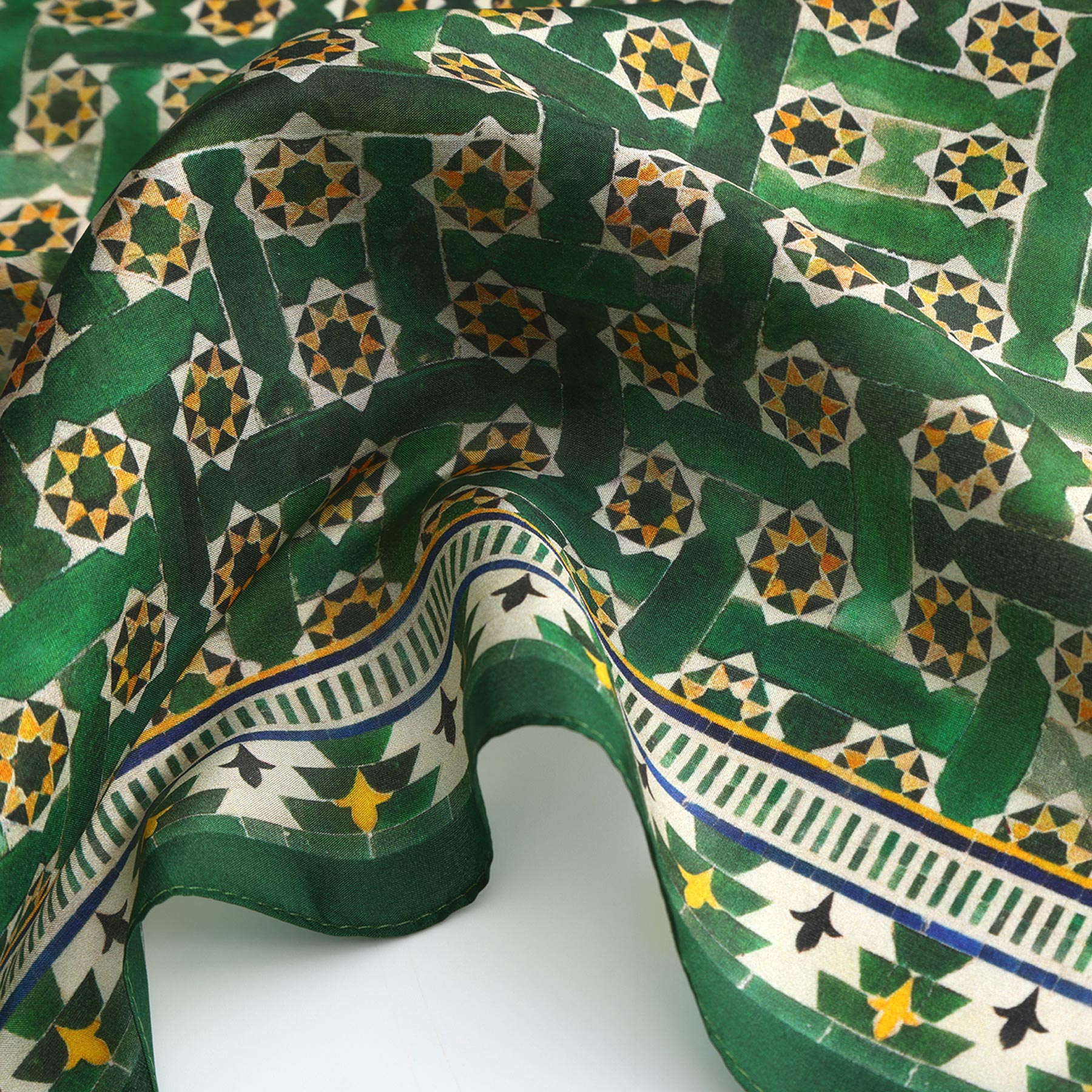 A close-up of the Green Square Scarf Silk, showcasing an intricate geometric and star pattern inspired by Islamic art, with yellow and white accents and a decorative Alhambra Palace-inspired border.