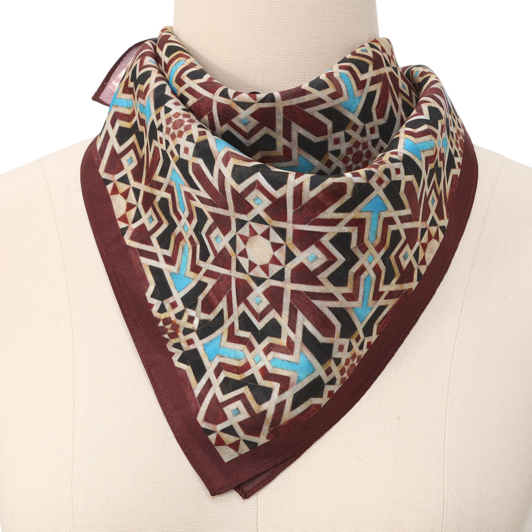 Brown Silk Neckerchief featuring a geometric, star-patterned design inspired by Islamic art in maroon, gold, black, white, and blue tones with a maroon border, elegantly draped around a mannequin’s neck.