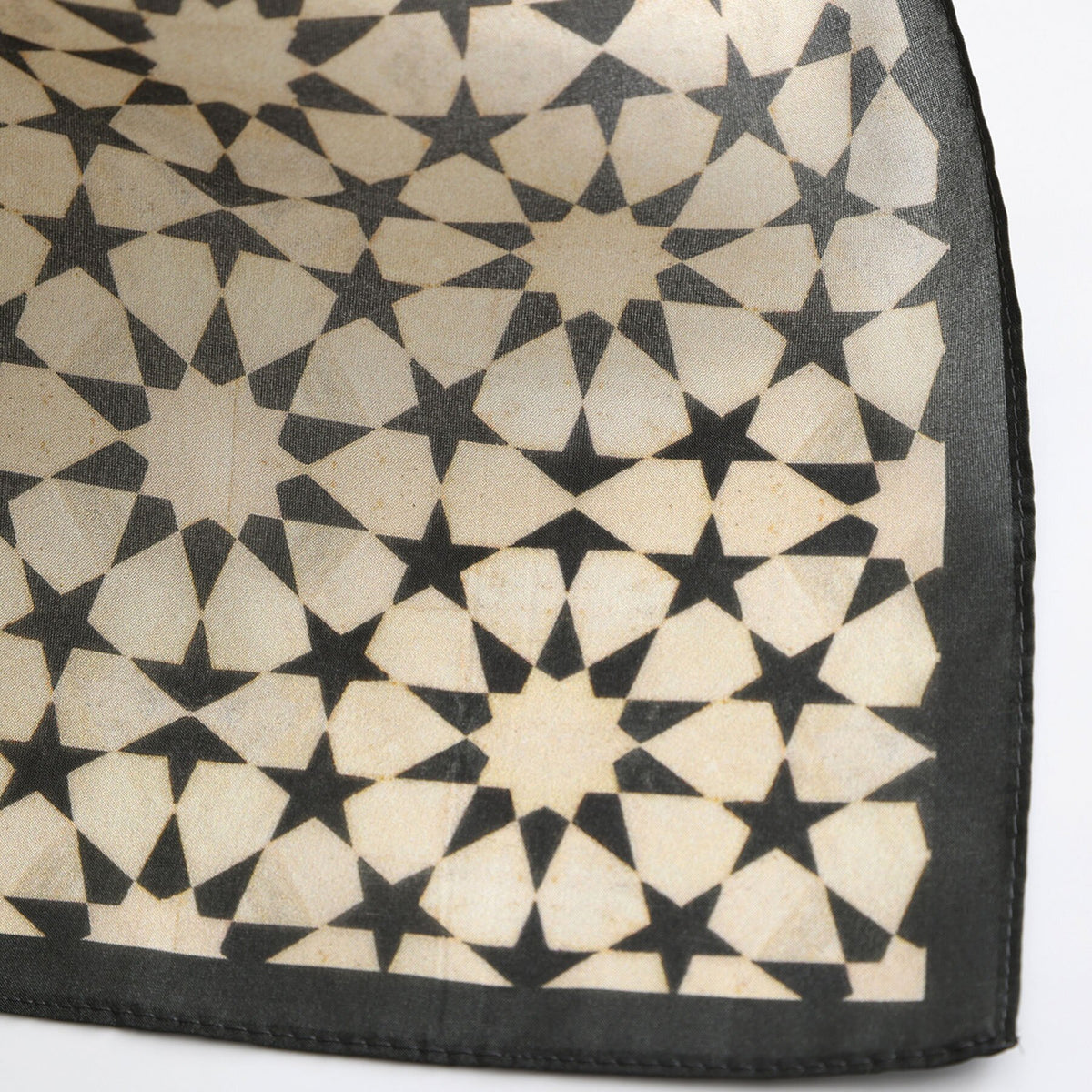 Close-up of the Nujum silk print: the charcoal star lattice on cream