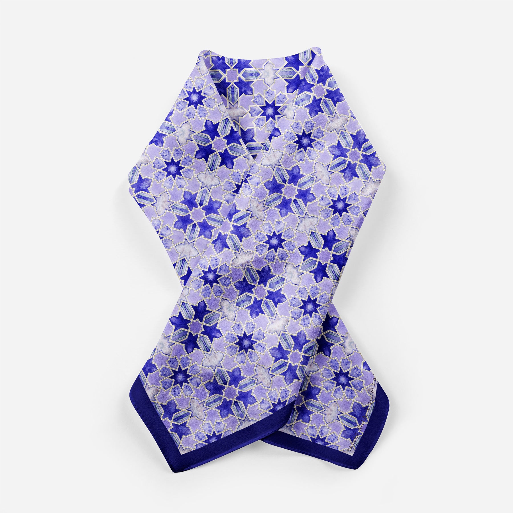 The Square Silk Scarf for Women Purple features a vibrant blue and purple floral pattern on a white background with dark blue edges, neatly folded.