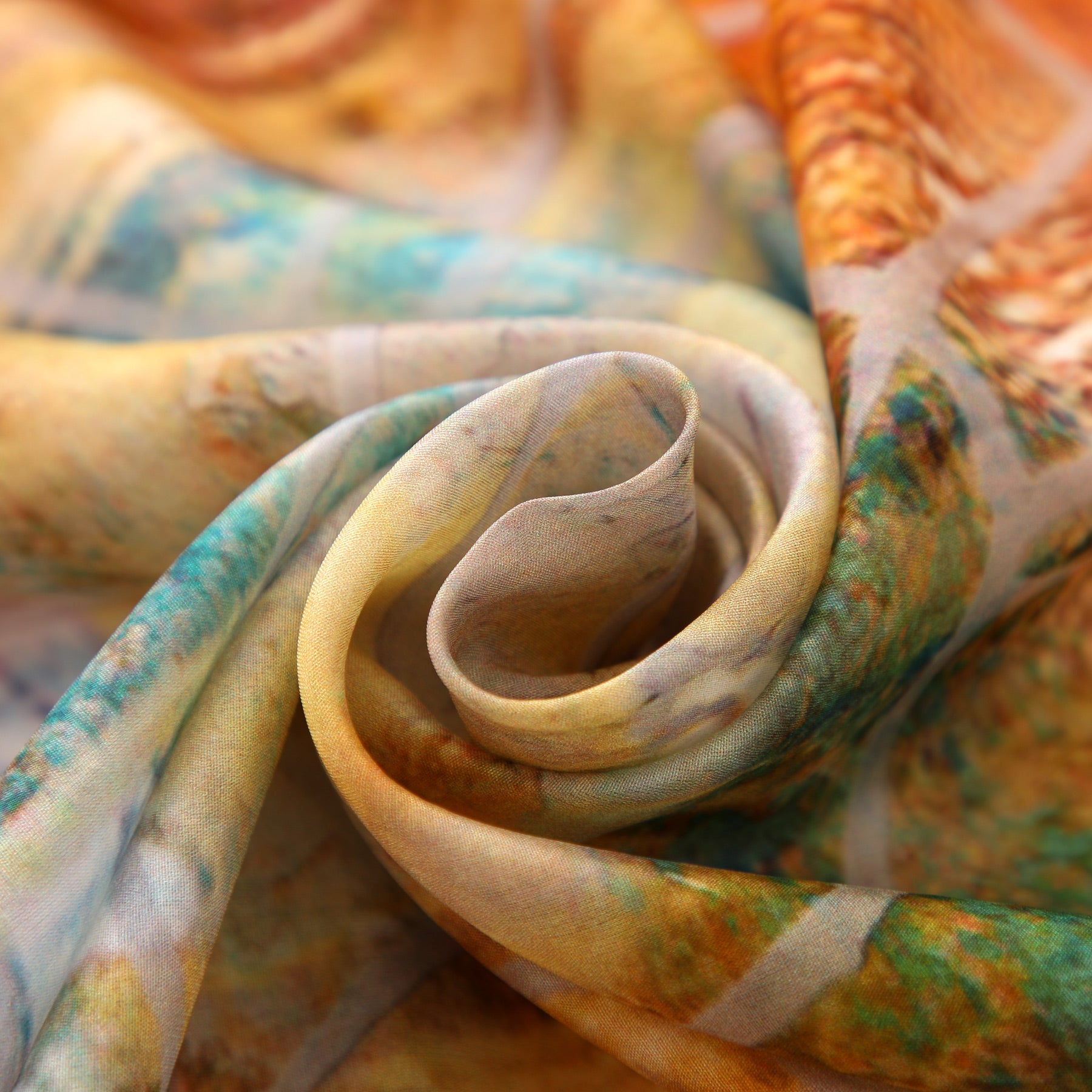 A close-up of the Artisan Silk Scarf Estrellas del Templo, a colorful, translucent Mediterranean accessory with swirls of yellow, green, orange, and blue, artistically folded in a spiral.