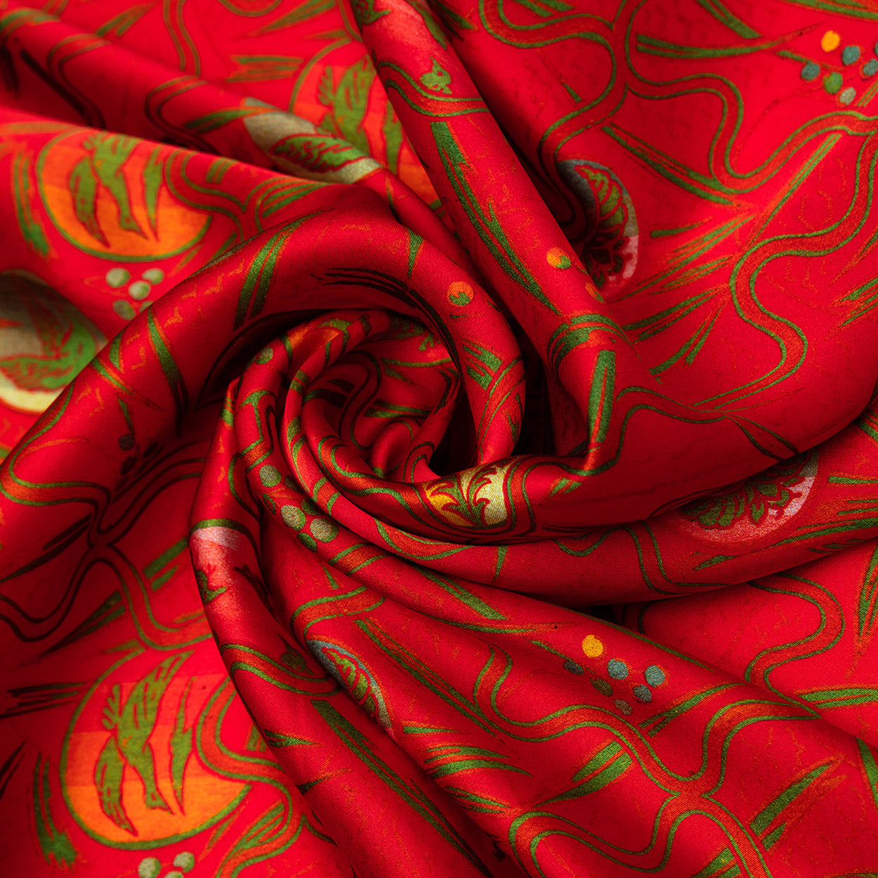 Swirled section of a bright red silk scarf featuring bold green and gold shapes in a flowing, abstract design reminiscent of artisanal artwork.