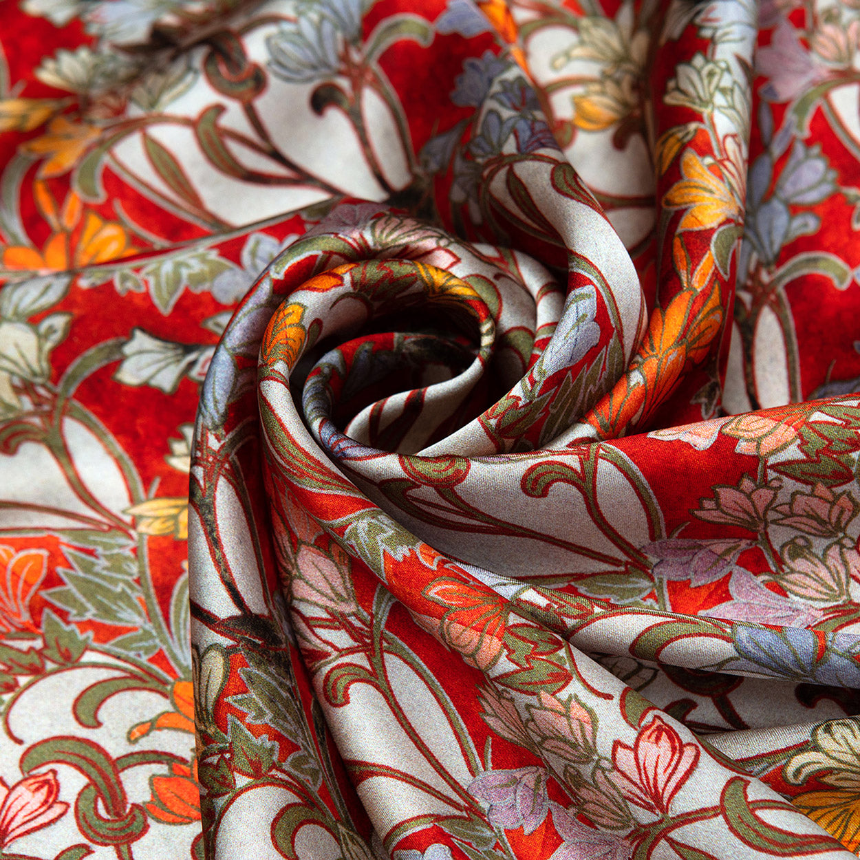 Swirled close-up showing the scarf’s intricate art deco-inspired florals in warm red, orange, and soft pastel hues.