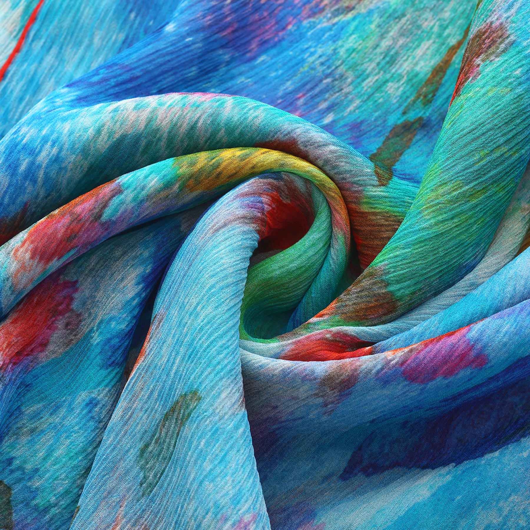 Close-up of the Multicolor Silk Scarf Mar Rojo in muslin silk, showcasing swirling folds and a watercolor-inspired mix of blue, green, red, and yellow—wearable artwork in vibrant hues.