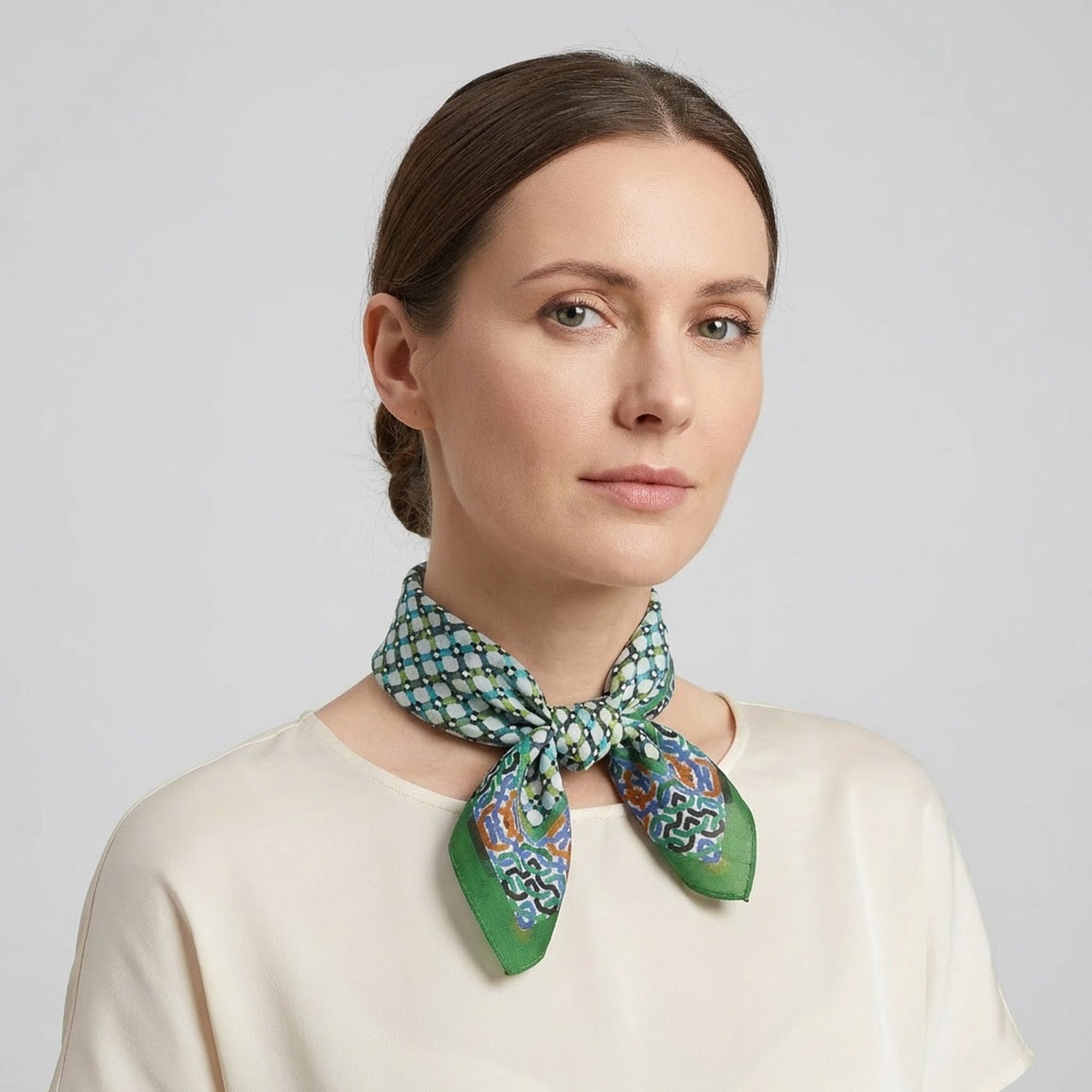 A woman with brown hair pulled back wears a cream blouse and the Coloful Neckerchief 100% Silk, tied neatly around her neck. She faces forward with a neutral expression against a plain background.