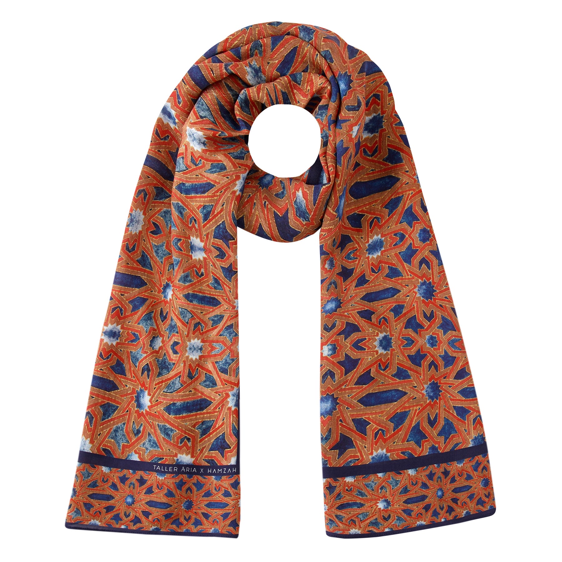 The Moorish Tiles Inspired Modal Scarf - Alcázar Genil features an intricate orange, blue, and white geometric pattern with star shapes and floral motifs, inspired by Andalusí Islamic art. The scarf is styled in a loose, elegant loop.