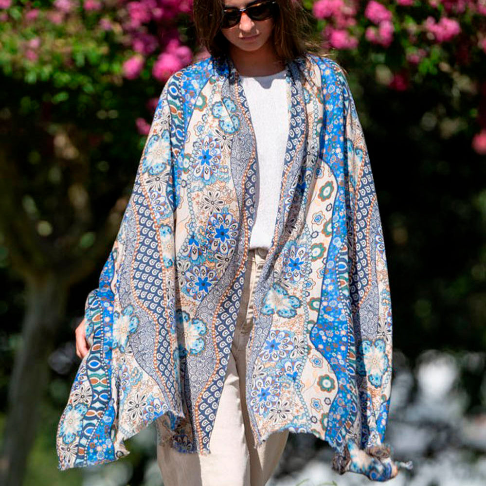 Elegant woman wearing a luxurious blue silk scarf with intricate floral and geometric patterns, styled in a bohemian look. A sophisticated and lightweight accessory for any occasion.