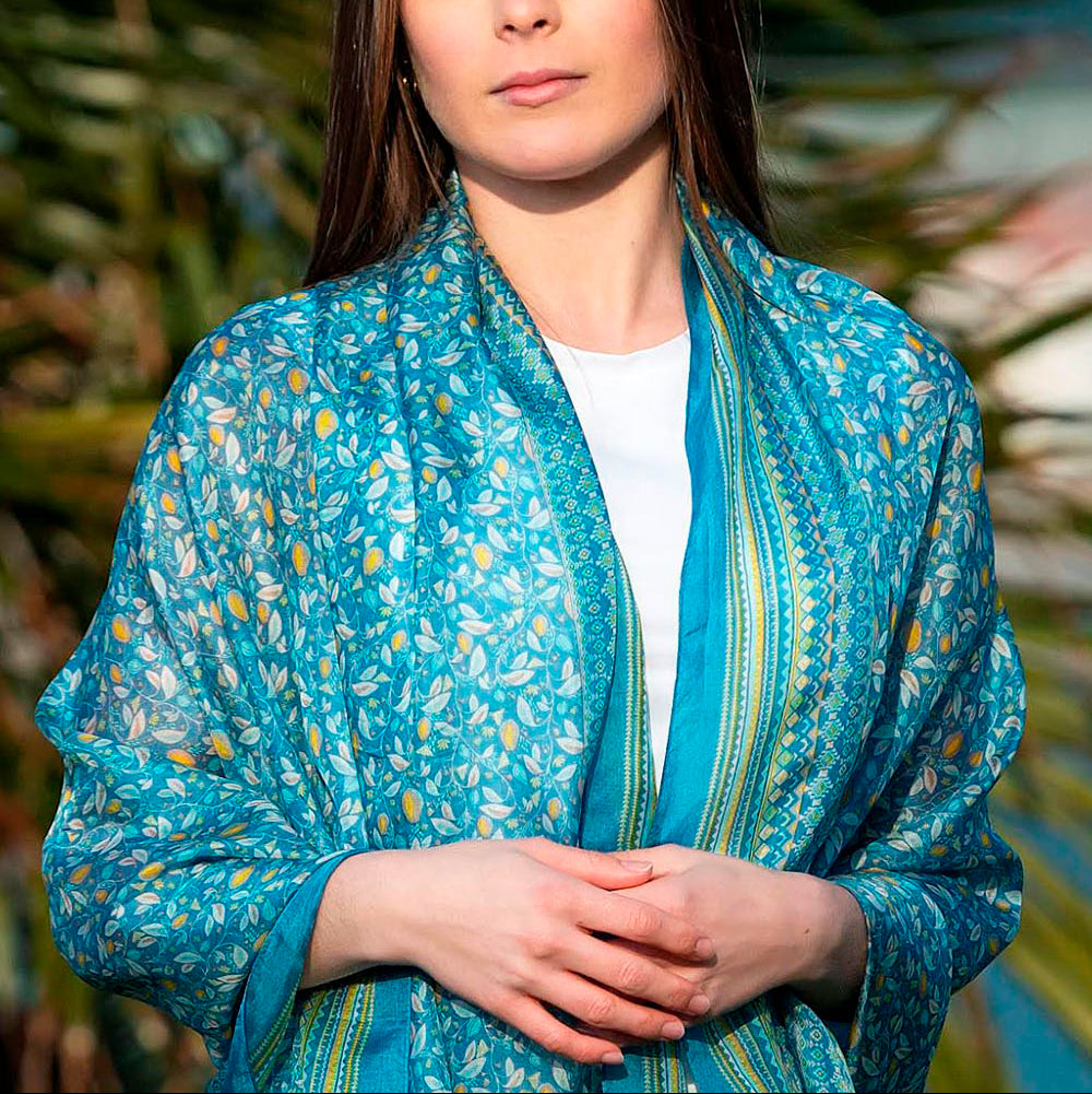 Close-up of a model wearing an elegant blue silk scarf with intricate floral print, highlighting its luxurious texture and design.