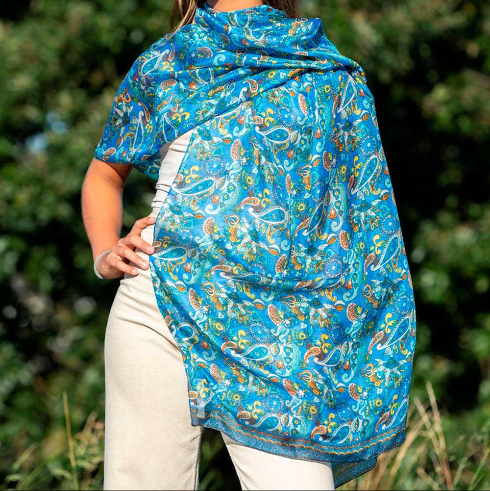 Front view of a vibrant blue silk scarf with intricate paisley and Islamic-inspired patterns, elegantly draped over a model outdoors.