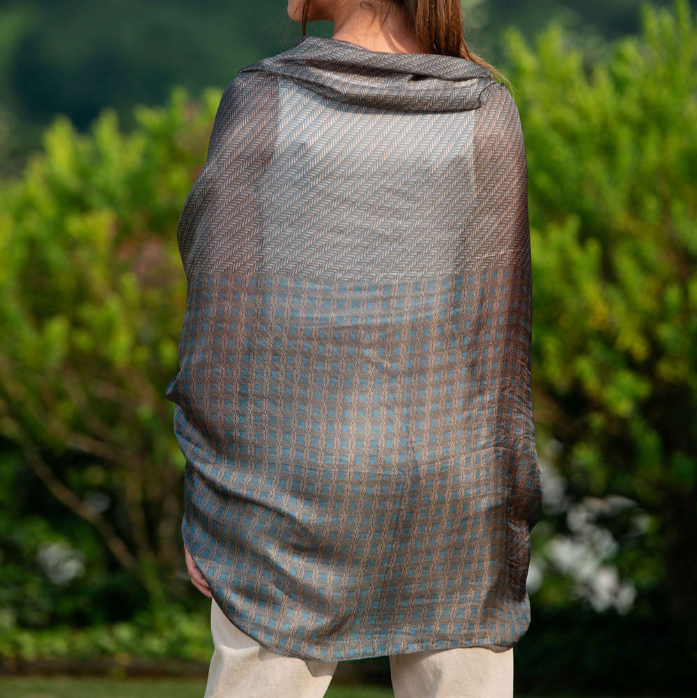 Back view of a luxurious dark blue silk scarf with Greek key and geometric patterns, elegantly draped over a model in an outdoor setting.