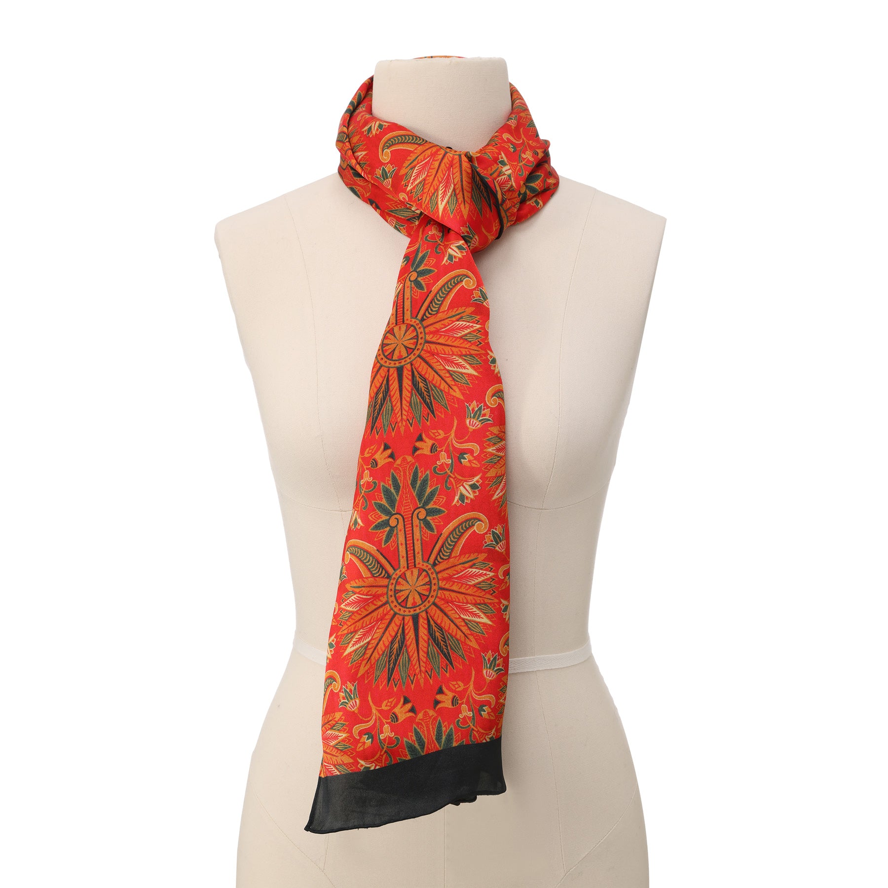 Close-up of a red silk scarf with golden and green floral motifs, neatly rolled into a spiral to highlight its lustrous texture and intricate design.
