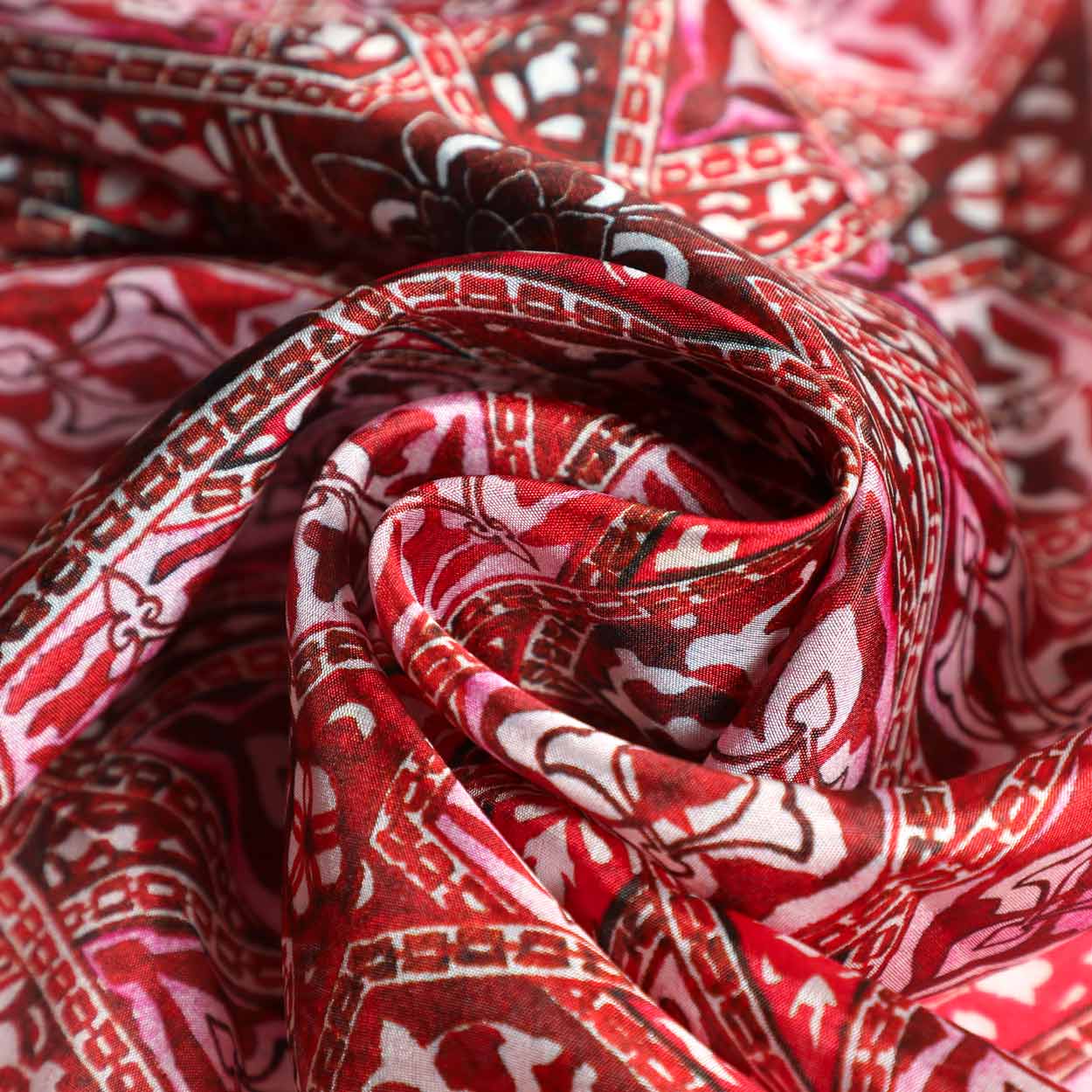 Close-up of luxurious red silk scarf featuring intricate Andalusian-inspired Islamic patterns. The fine fabric drapes elegantly, showcasing the rich details and vibrant color palette.