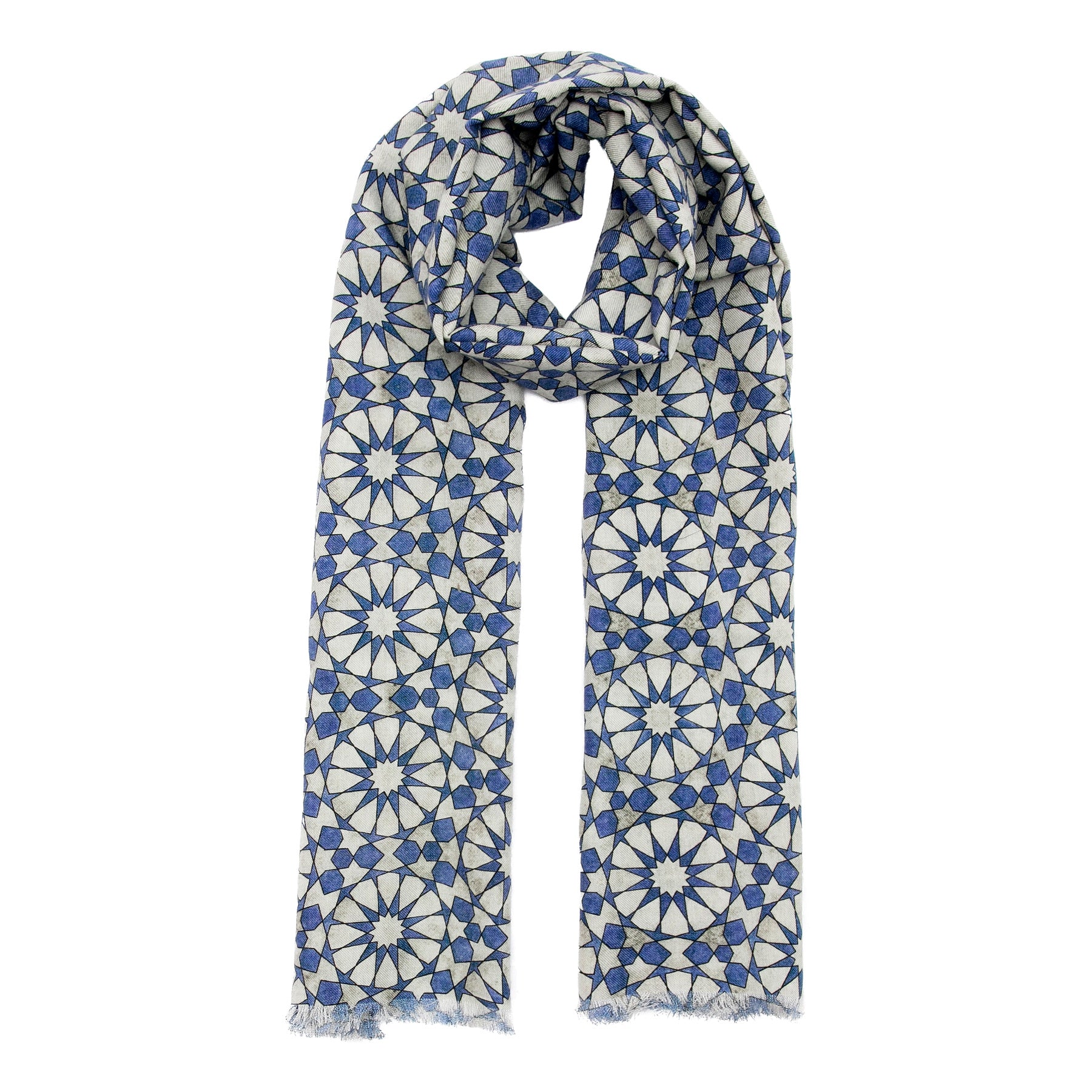 The Hamzah Silk and Wool Scarf features an intricate geometric pattern inspired by Islamic art, displaying blue and gray starburst designs. The luxuriously soft fabric drapes elegantly, with fringed edges adding a sophisticated touch.