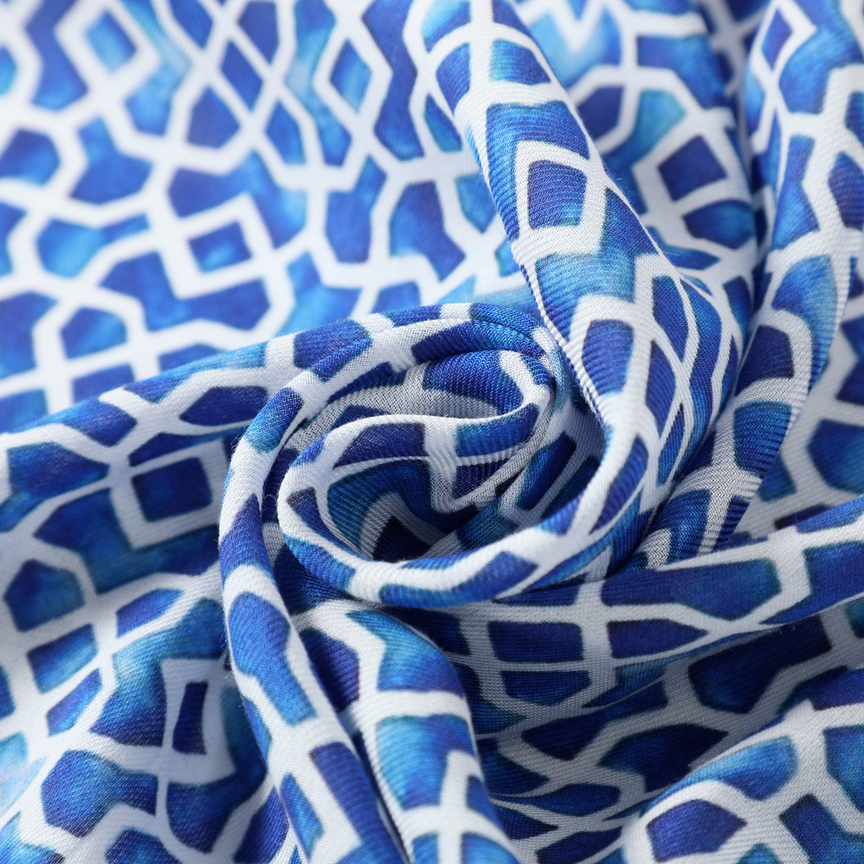 Close-up texture detail of a silk scarf with Islamic-inspired blue and white patterns.