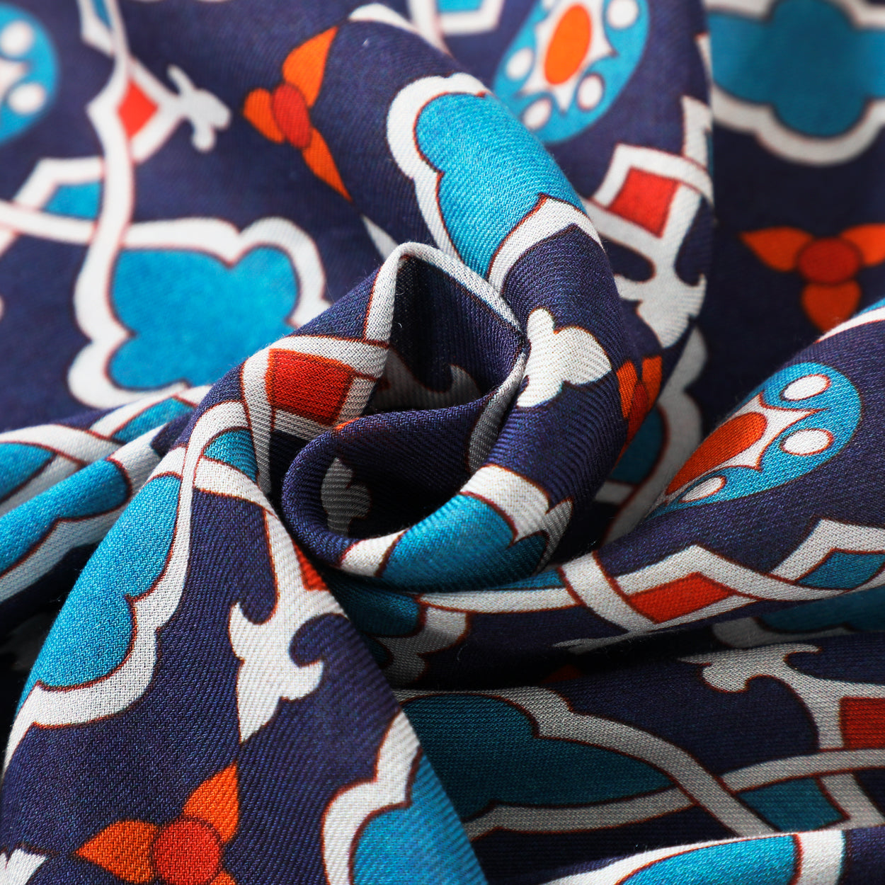 Close-up texture detail of the geometric navy blue and red Islamic art-inspired scarf.