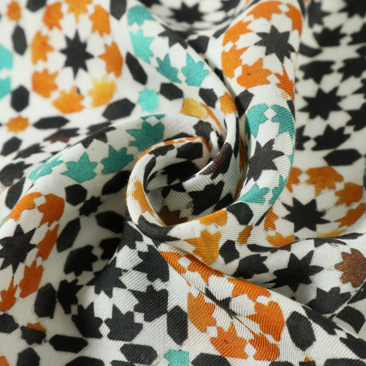 Close-up texture detail of green and orange modal scarf with Islamic art print.