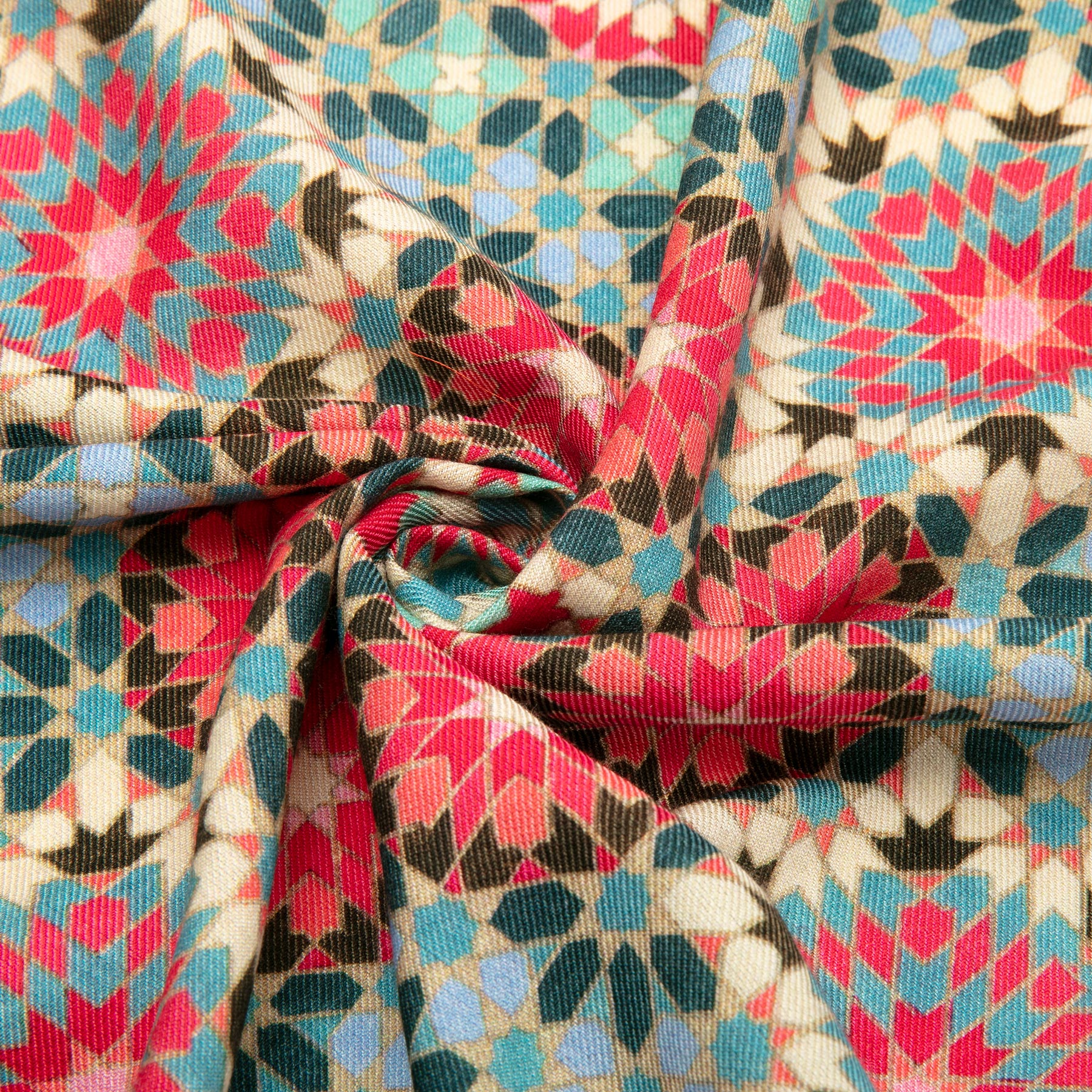 Experience the luxurious design of Hamzahs Large Silk and Wool Multicolor Scarf Baraka V1. It showcases a geometric star print in red, blue, teal, and white on beige. The partly gathered fabric elegantly spirals at the center.