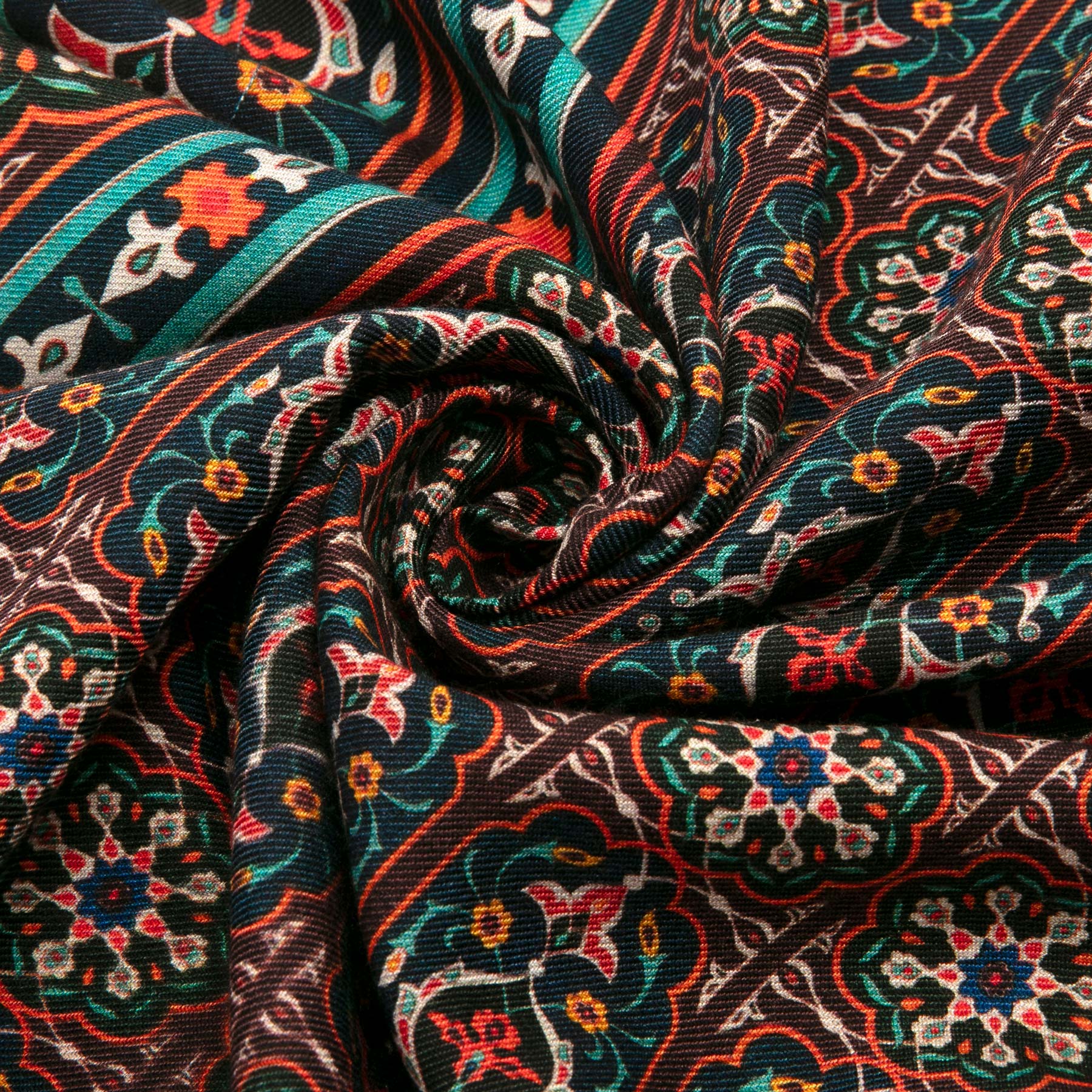 Close-up of a dynamic spiral in the Silk and Wool Large Scarf Zarafshan by Hamzah, featuring vibrant floral and geometric designs reminiscent of Islamic art, in shades of red, teal, white, and yellow. Its intricate patterns create a vibrant visual effect.