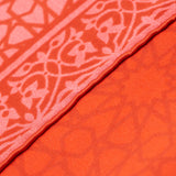 Hand-rolled detail of red square scarf featuring islamic art design